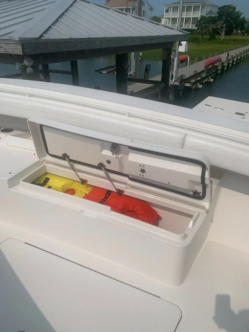Slide: The Image of An open storage compartment on a boat reveals life jackets. A dock is visible in the background. - 24
