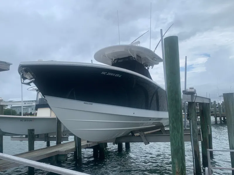 Slide: The Image of A 2020 Regulator 31 boat is docked. It features a dark hull and a white upper deck. - 2