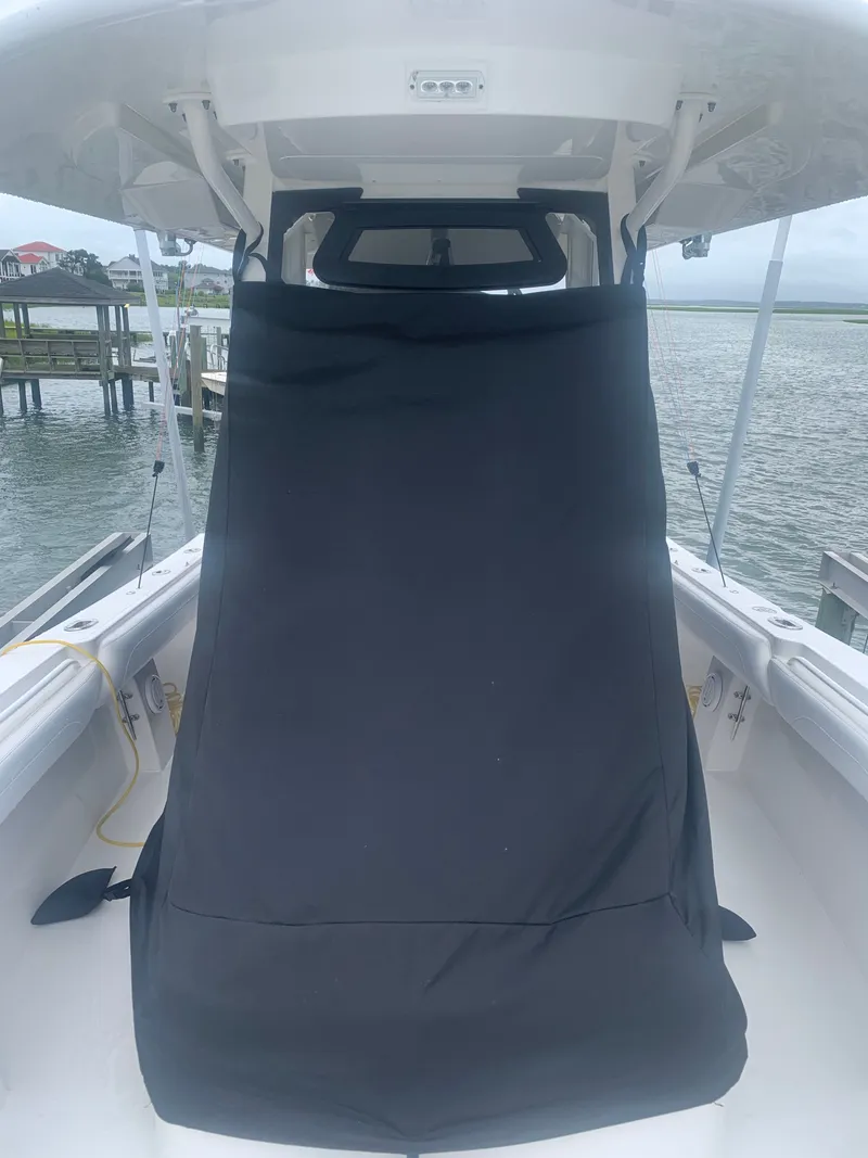 Slide: The Image of A 2020 Regulator 31 boat with a black cover in the cockpit area, docked by the water. - 23