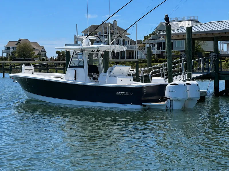 Slide: The Image of A 2020 Regulator 31 boat is docked in the water. Houses are visible in the background. - 20