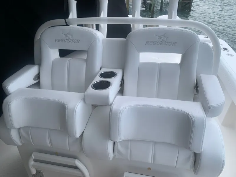 Slide: The Image of Two white cushioned boat seats with cup holders on a 2020 Regulator 31, near the water. - 7