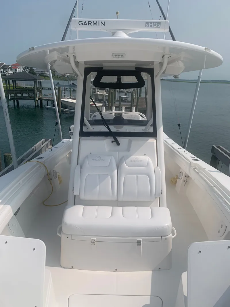Slide: The Image of A 2020 Regulator 31 boat with a white seating area and Garmin equipment, docked at a calm harbor. - 22