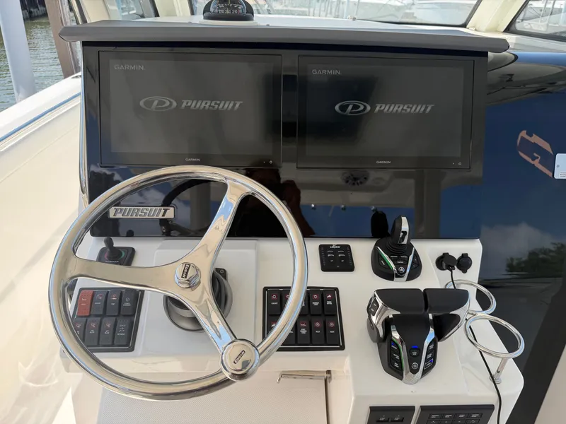 Slide: The Image of The image shows the helm of a Pursuit S 328 Sport with two Garmin screens and a steering wheel. - 16