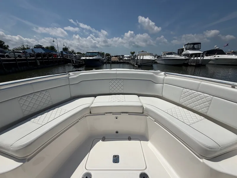 Slide: The Image of The image shows the spacious, cushioned bow area of a Pursuit S 328 Sport boat in a marina. - 23