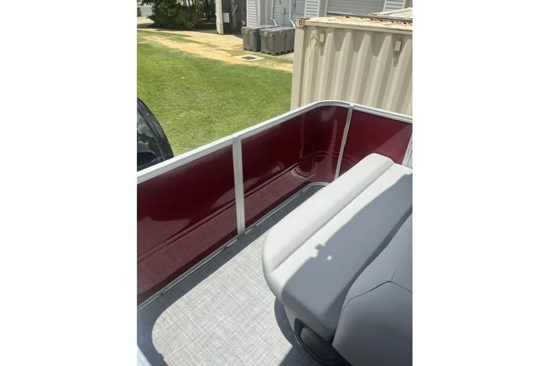 Slide: The Image of 2026 SUNTRACKER pb18 pontoon boat interior with red siding and gray seating. - 2