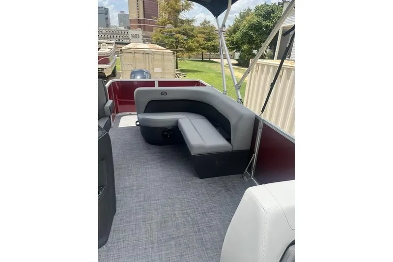 Slide: The Image of 2026 SUNTRACKER pb18 pontoon boat interior with gray seating and cityscape background. - 12