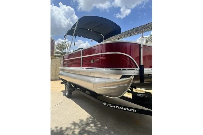 Slide: The Image of 2026 SUNTRACKER pb18 pontoon boat with red exterior and canopy on trailer. - 3