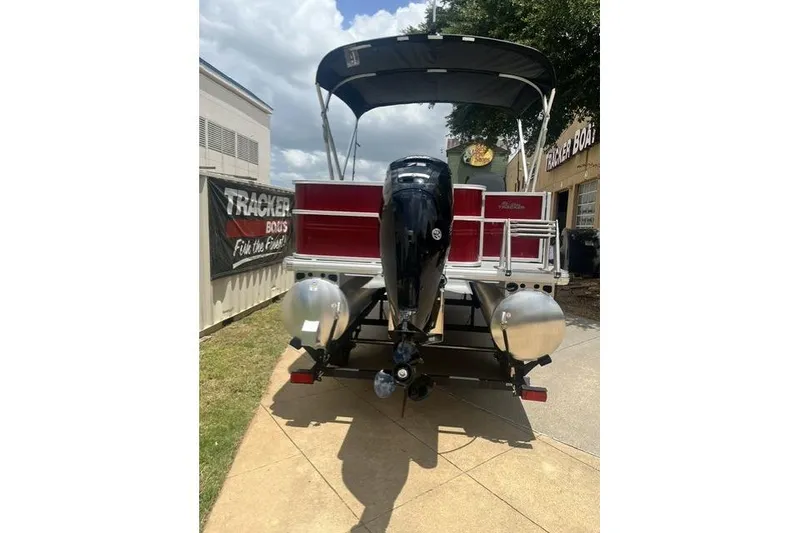 Slide: The Image of 2026 SUNTRACKER pb18 pontoon boat with outboard motor, parked outdoors. - 6