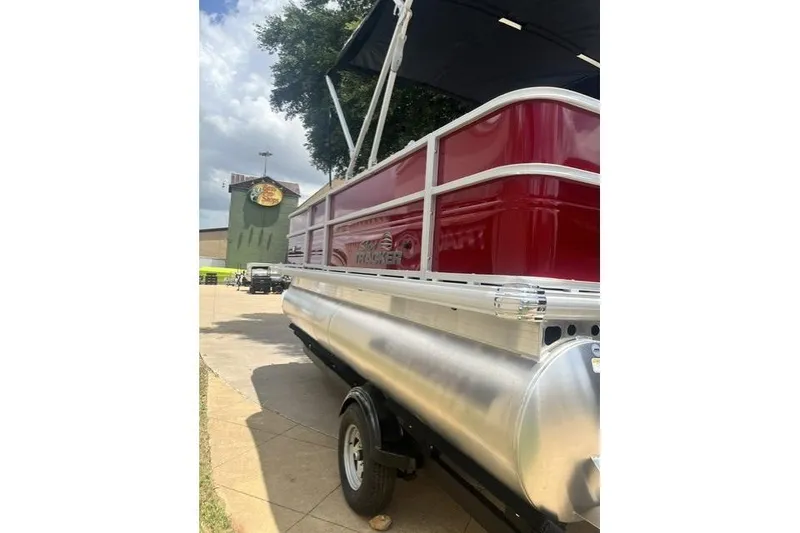 Slide: The Image of 2026 SUNTRACKER pb18 pontoon boat with red exterior, parked outdoors. - 7