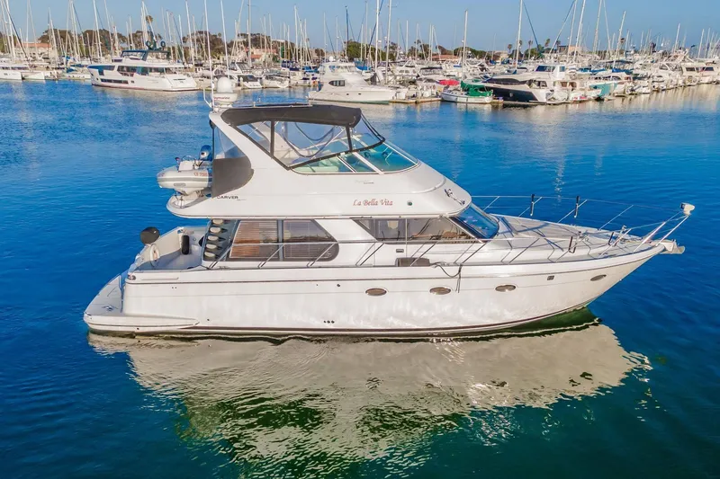 Slide: The Image of 2000 Carver 450 Voyager Pilothouse yacht docked in a marina, surrounded by boats. - 11
