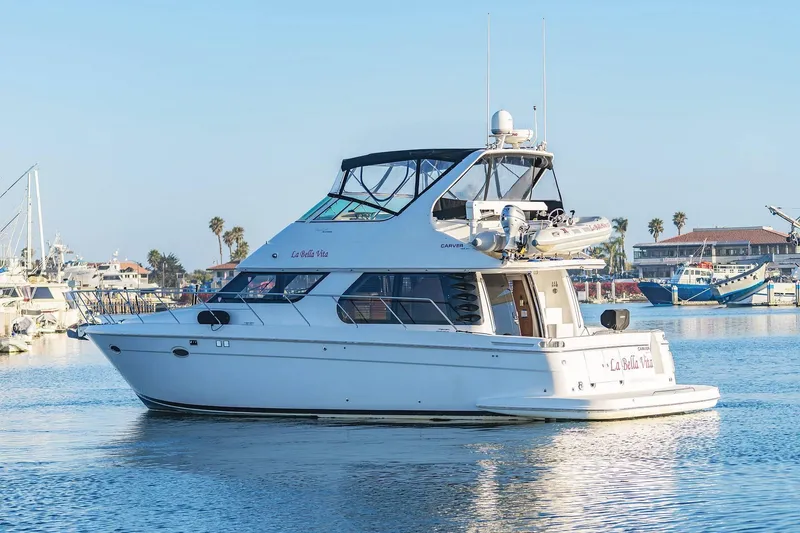 Slide: The Image of 2000 Carver 450 Voyager Pilothouse yacht docked in a sunny marina. - 2