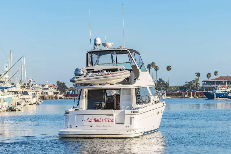 Slide: The Image of 2000 Carver 450 Voyager Pilothouse yacht in marina, clear sky, palm trees in background. - 5