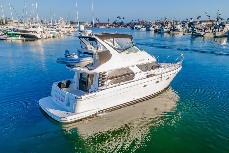 Slide: The Image of A 2000 Carver 450 Voyager Pilothouse yacht docked in a marina under clear blue skies. - 14