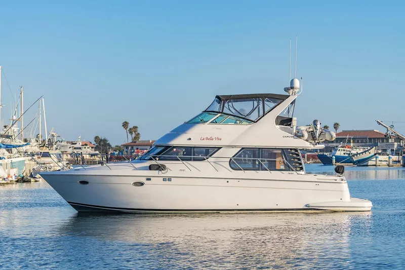 Slide: The Image of 2000 Carver 450 Voyager Pilothouse yacht docked in a sunny marina. - 1