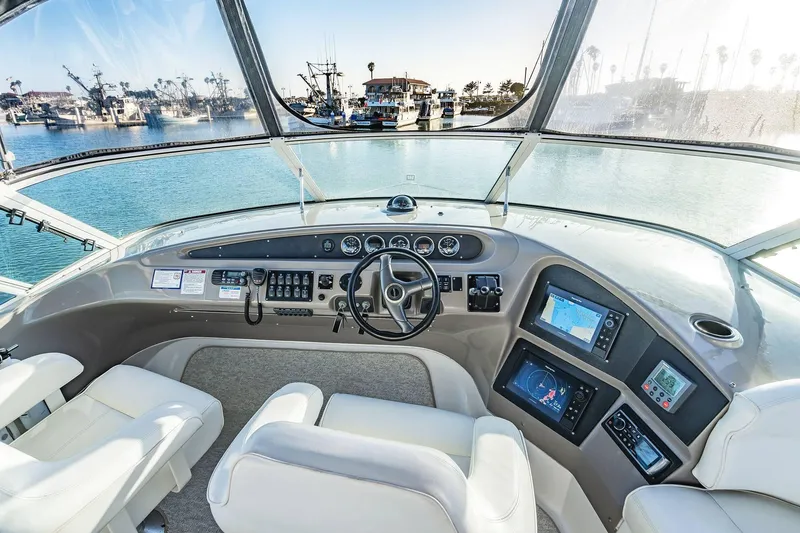 Slide: The Image of Pilothouse interior of 2000 Carver 450 Voyager, featuring navigation controls and panoramic harbor view. - 26