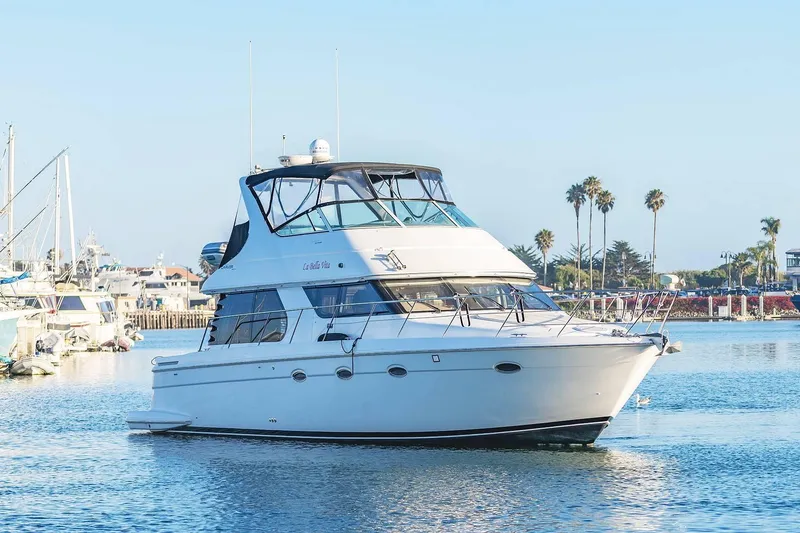 Slide: The Image of 2000 Carver 450 Voyager Pilothouse yacht cruising in a sunny marina setting. - 8