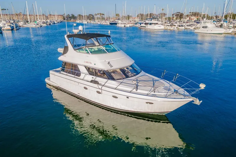Slide: The Image of 2000 Carver 450 Voyager Pilothouse yacht docked in a marina, surrounded by sailboats. - 12
