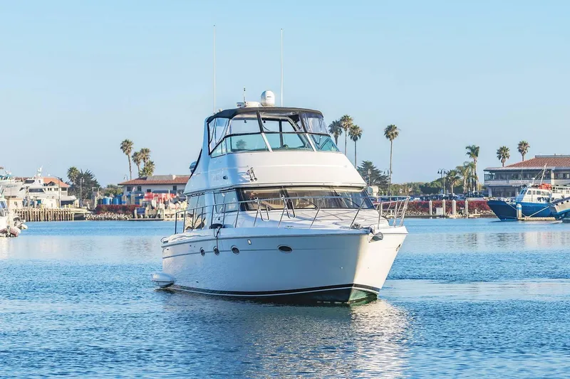 Slide: The Image of 2000 Carver 450 Voyager Pilothouse yacht cruising in a sunny marina setting. - 9