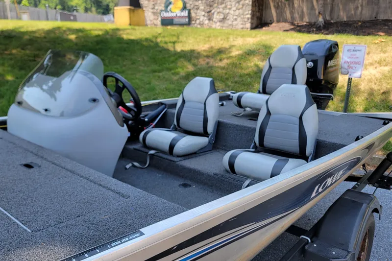 Slide: The Image of 2013 Lowe Skorpion boat with seating and steering wheel, parked outdoors. - 5