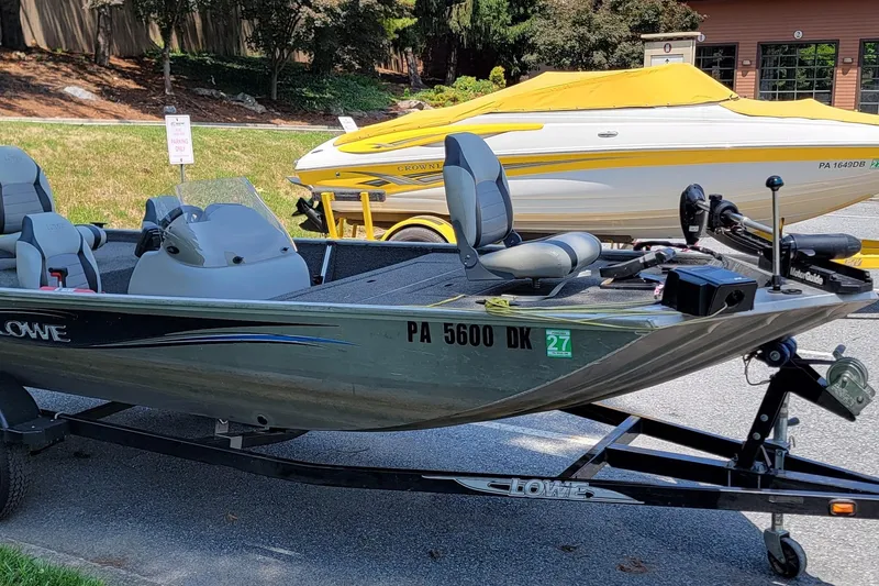 Slide: The Image of 2013 Lowe Skorpion boat on trailer, parked outdoors with another boat in the background. - 6