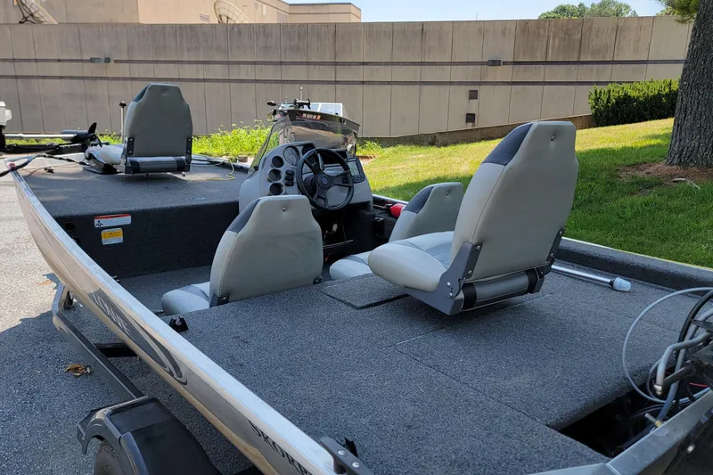 Slide: The Image of 2013 Lowe Skorpion boat interior with steering console and seating, parked outdoors. - 3