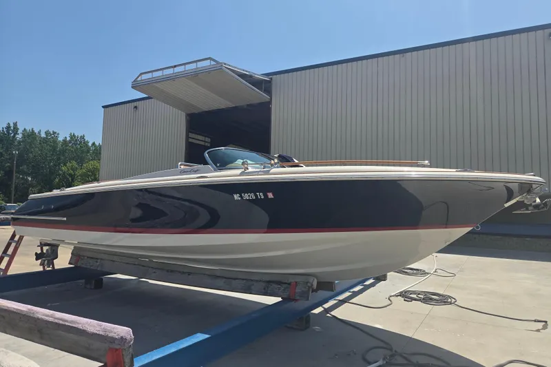 Slide: The Image of 2013 Chris-Craft Corsair 28 boat on a trailer outside a large building. - 0