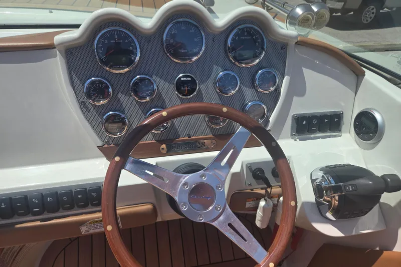 Slide: The Image of 2013 Chris-Craft Corsair 28 dashboard with wooden steering wheel and control gauges. - 11