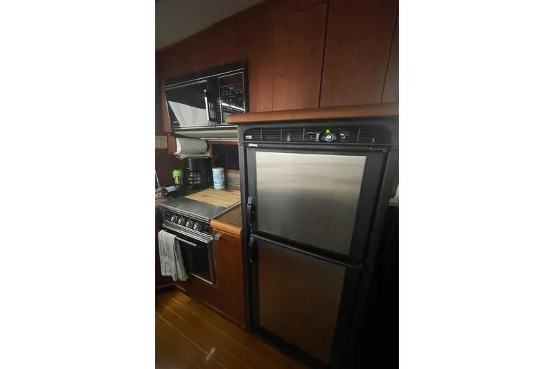 Slide: The Image of 1988 Bayliner 4588 Pilothouse kitchen with stainless steel appliances and wooden cabinetry. - 7