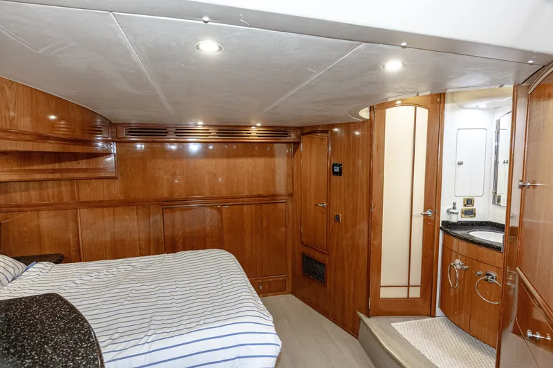 Slide: The Image of The 2002 Carver 530 Voyager Pilothouse cabin features a bed, wooden walls, and a bathroom. - 17