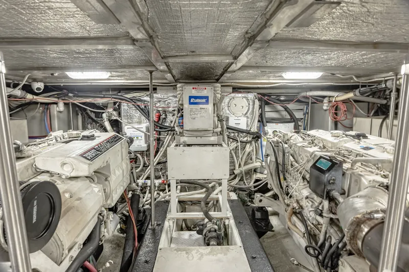 Slide: The Image of The engine room of a 2002 Carver 530 Voyager Pilothouse with two large engines and wiring. - 34