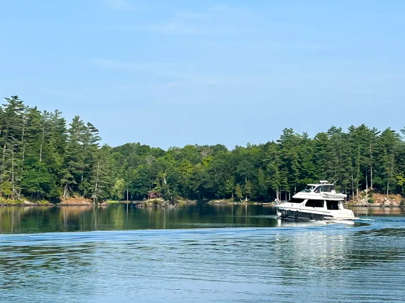 Slide: The Image of A 2002 Carver 530 Voyager Pilothouse cruising on a calm lake, surrounded by trees. - 1