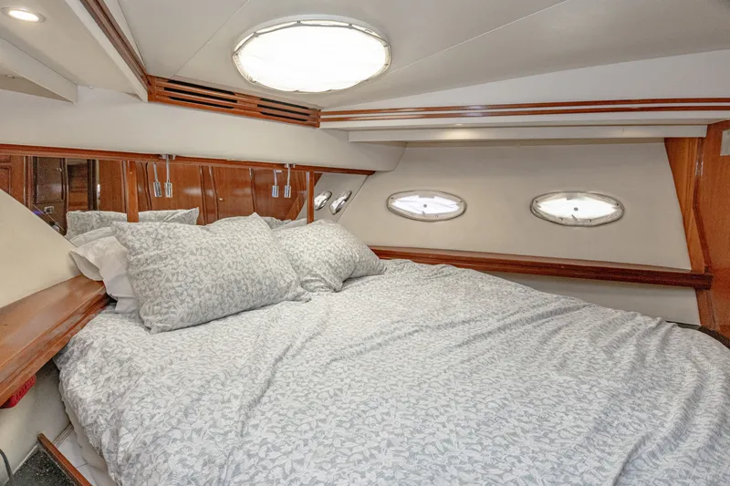 Slide: The Image of The 2002 Carver 530 Voyager Pilothouse cabin features a cozy bed with elegant wood accents. - 25