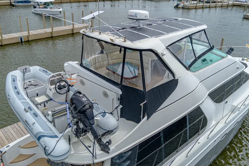 Slide: The Image of The 2002 Carver 530 Voyager Pilothouse is docked. A dinghy is on the deck. - 40