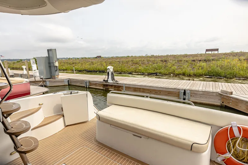 Slide: The Image of The 2002 Carver 530 Voyager Pilothouse is docked in a serene setting. It features a spacious aft deck with comfortable seating and a sleek staircase. - 32