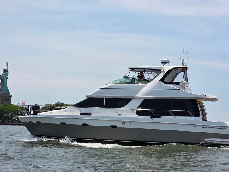 Slide: The Image of A 2002 Carver Voyager Pilothouse 530 cruising on the water, with the Statue of Liberty in the background. - 2