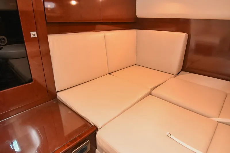 Slide: The Image of Interior seating area of 2008 Sea Ray 38 Sundancer with beige cushions and wooden paneling. - 38