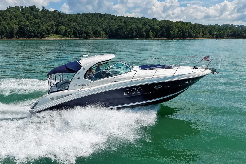 The Image of 2008 Sea Ray 38 Sundancer cruising on a scenic lake with lush green shoreline. - 2