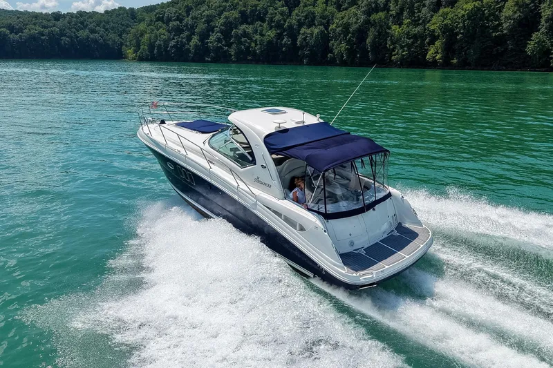 Slide: The Image of 2008 Sea Ray 38 Sundancer cruising on a serene lake with lush green surroundings. - 3