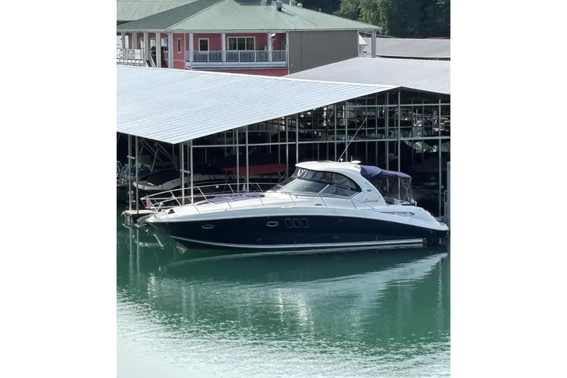 The Image of 2008 Sea Ray 38 Sundancer yacht docked at a marina, reflecting on calm water. - 0