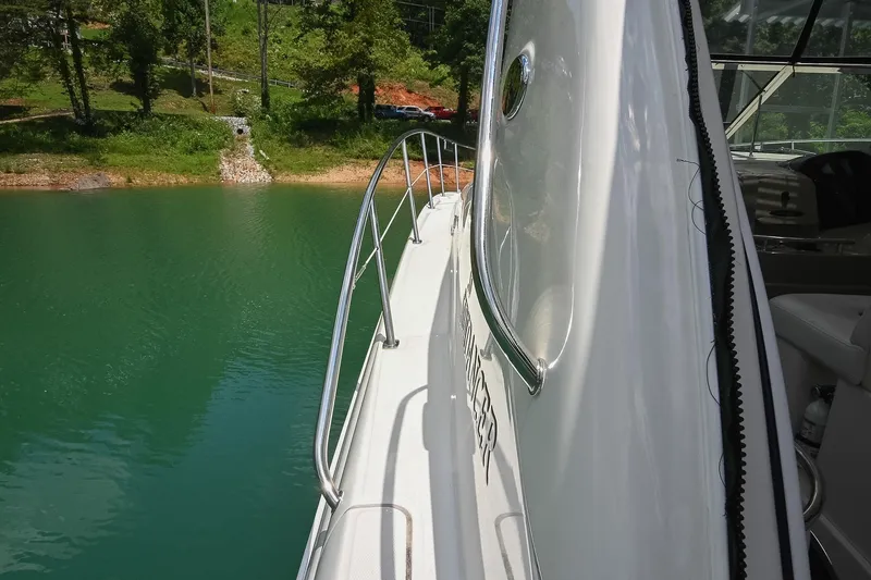 Slide: The Image of 2008 Sea Ray 38 Sundancer yacht on serene green water near a lush shoreline. - 24
