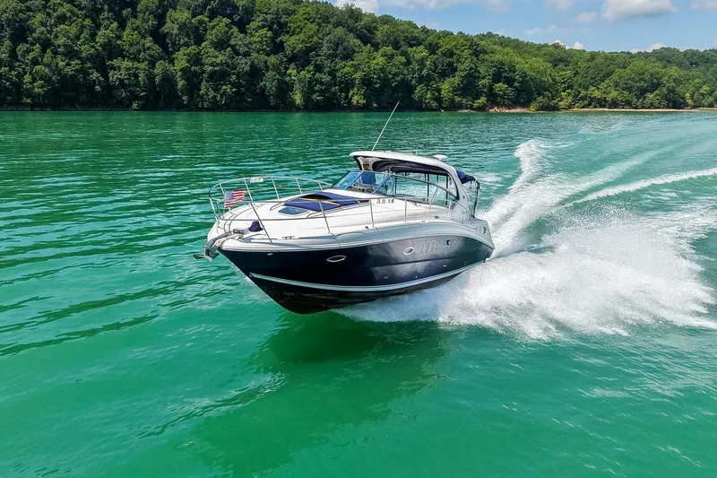 Slide: The Image of 2008 Sea Ray 38 Sundancer cruising on a vibrant green lake with forested shoreline. - 75