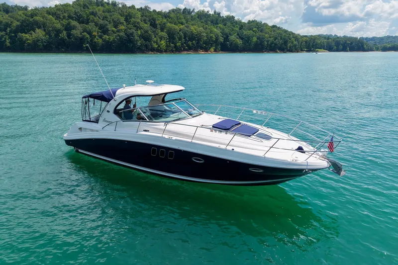 Slide: The Image of 2008 Sea Ray 38 Sundancer yacht cruising on a serene lake with lush green shoreline. - 70