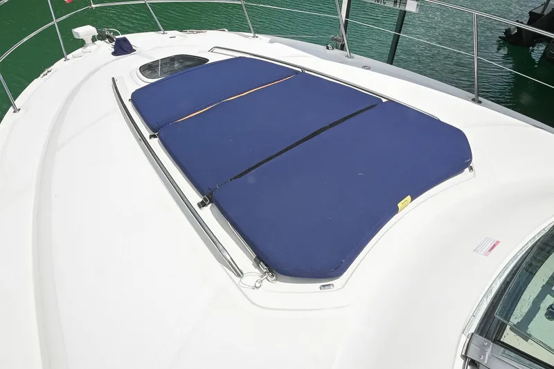 Slide: The Image of 2008 Sea Ray 38 Sundancer boat with blue sunpad on deck, docked on green water. - 27