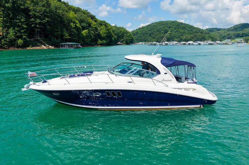 Slide: The Image of 2008 Sea Ray 38 Sundancer yacht on a serene lake with lush green hills. - 66