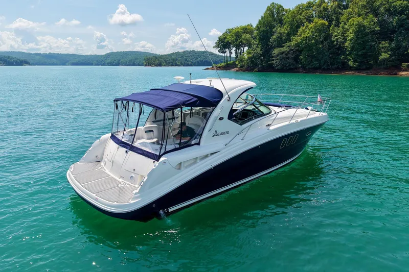 Slide: The Image of 2008 Sea Ray 38 Sundancer yacht on serene lake with lush green shoreline. - 63