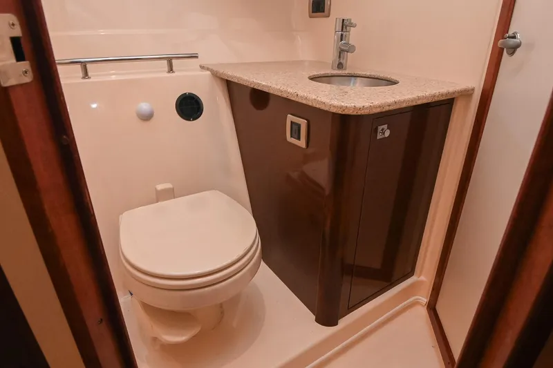 Slide: The Image of 2008 Sea Ray 38 Sundancer bathroom with toilet, sink, and wooden cabinetry. - 43