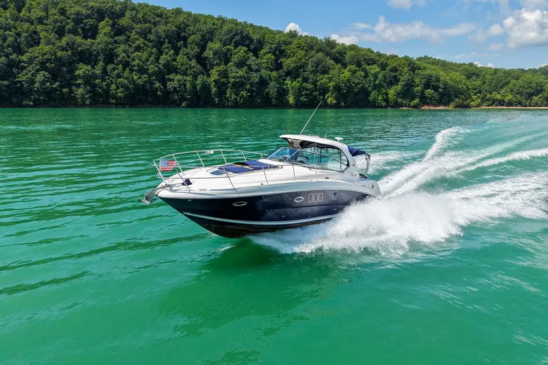 Slide: The Image of 2008 Sea Ray 38 Sundancer cruising on a vibrant green lake with forested shoreline. - 72