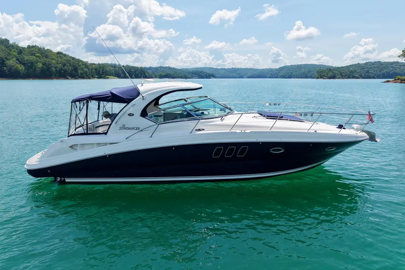 Slide: The Image of 2008 Sea Ray 38 Sundancer yacht on serene lake with lush green shoreline. - 67