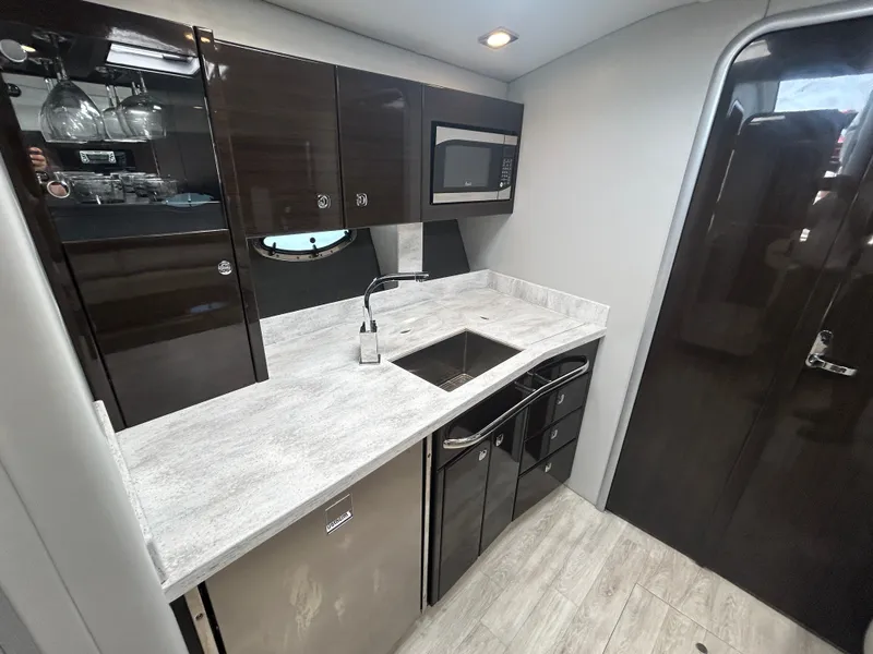 Slide: The Image of The 2017 Formula 37 Performance Cruiser's galley features dark cabinets, a sink, and modern appliances. - 40