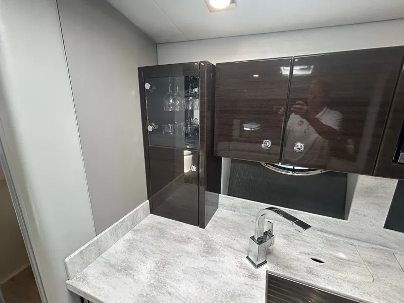 Slide: The Image of The yacht's galley features dark cabinets, a modern faucet, and a glassware cabinet. - 41